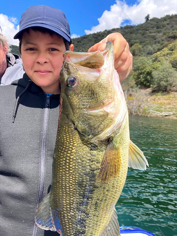 Enfant avec un bass à bout de bras sur lac portugais